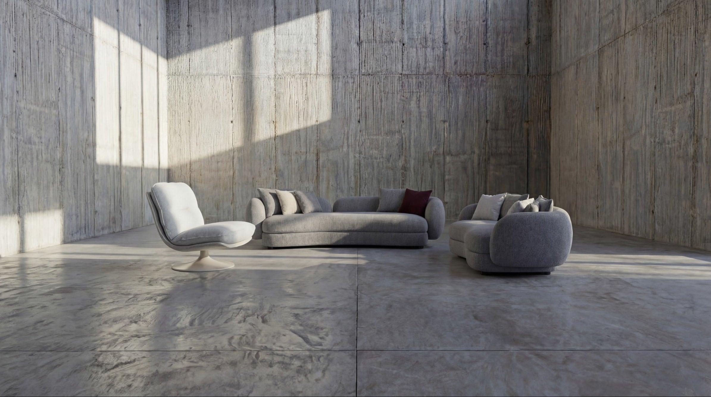 Modern gray sofa set in a minimalistic room with concrete walls and floor.